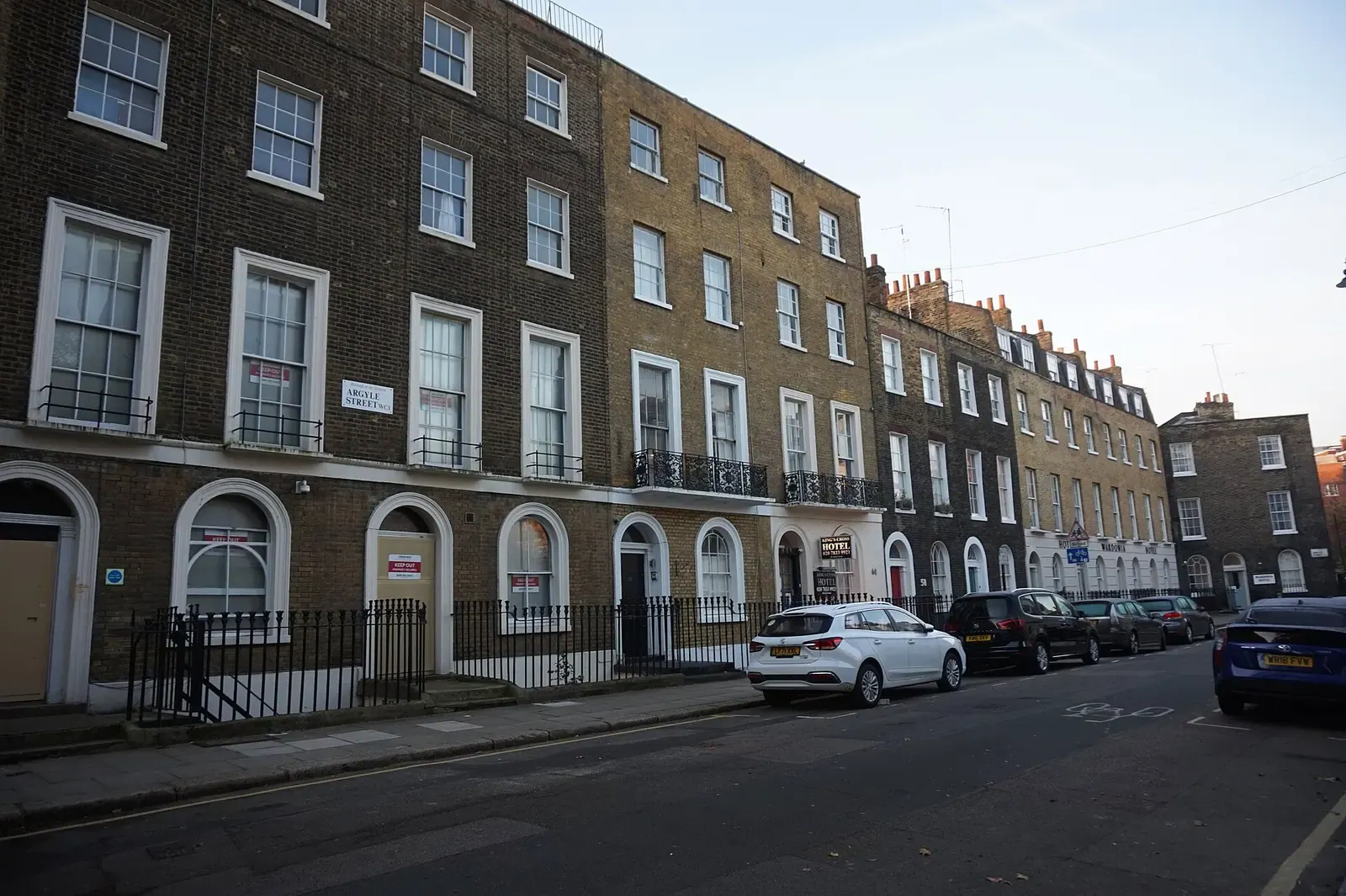 Georgian terrace of London stock brick houses with arched ground-floor windows and black railings on Argyle Street in Camden