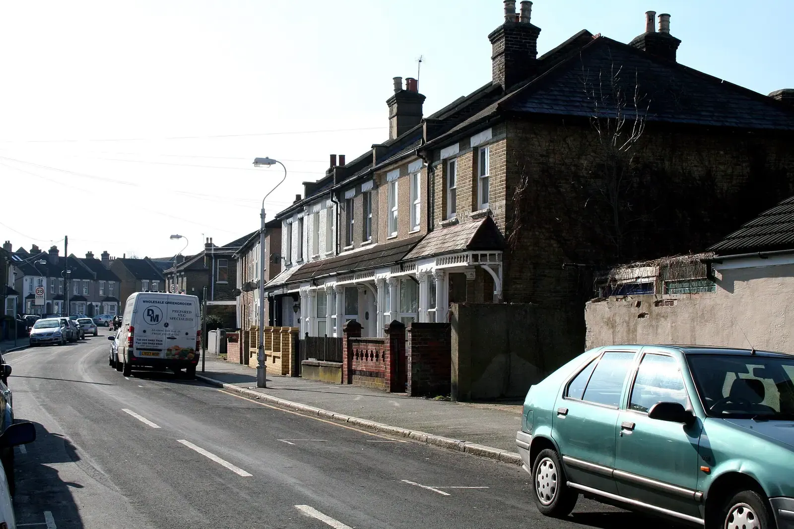 Terraced houses on Oval Road in Croydon with tiled roofs and a porch with white wooden fretwork, a white van parked on the street