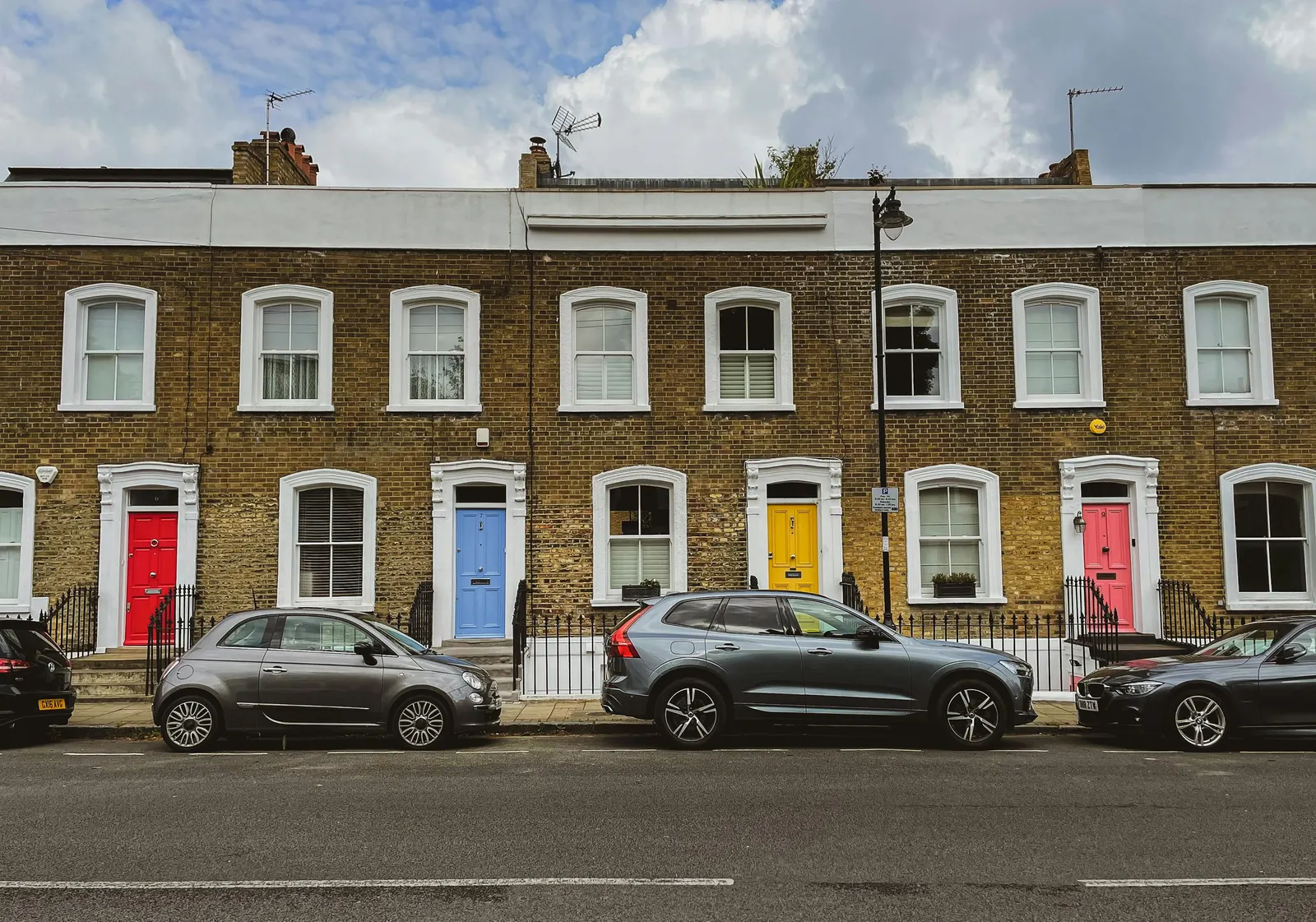Flat-fronted stock brick terrace with brightly painted front doors, the street context a design and access statement describes