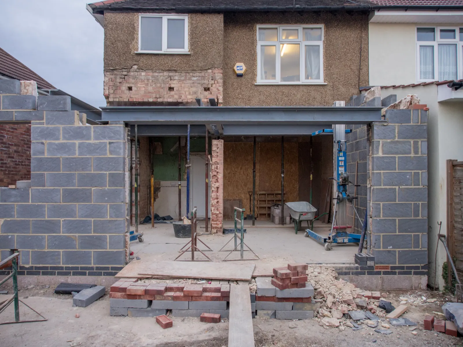 Rear extension under construction with blockwork walls and a steel beam opening up the back of a house