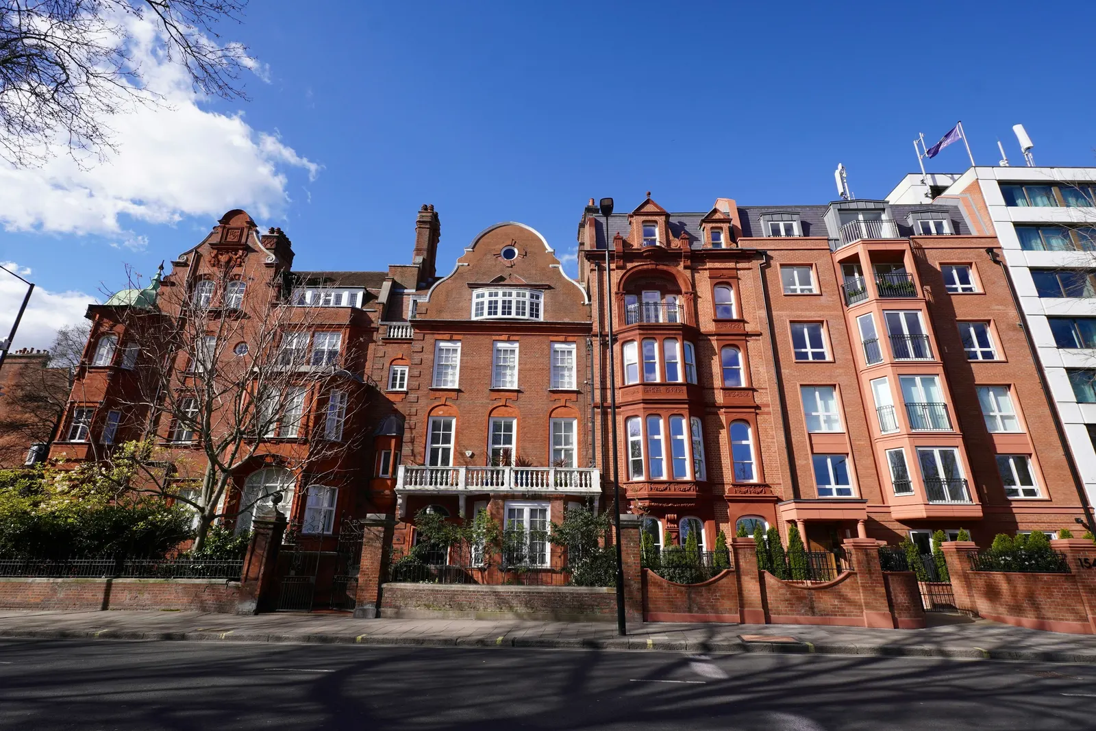Red-brick mansion blocks meeting on a Kensington street corner, a London building type already divided into flats