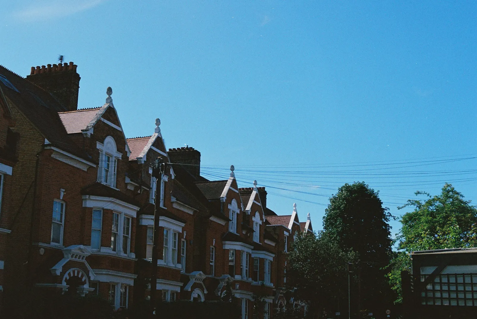 Red-brick terrace with white-painted gables and finials, a house type whose walls are rarely square or the same on any two floors