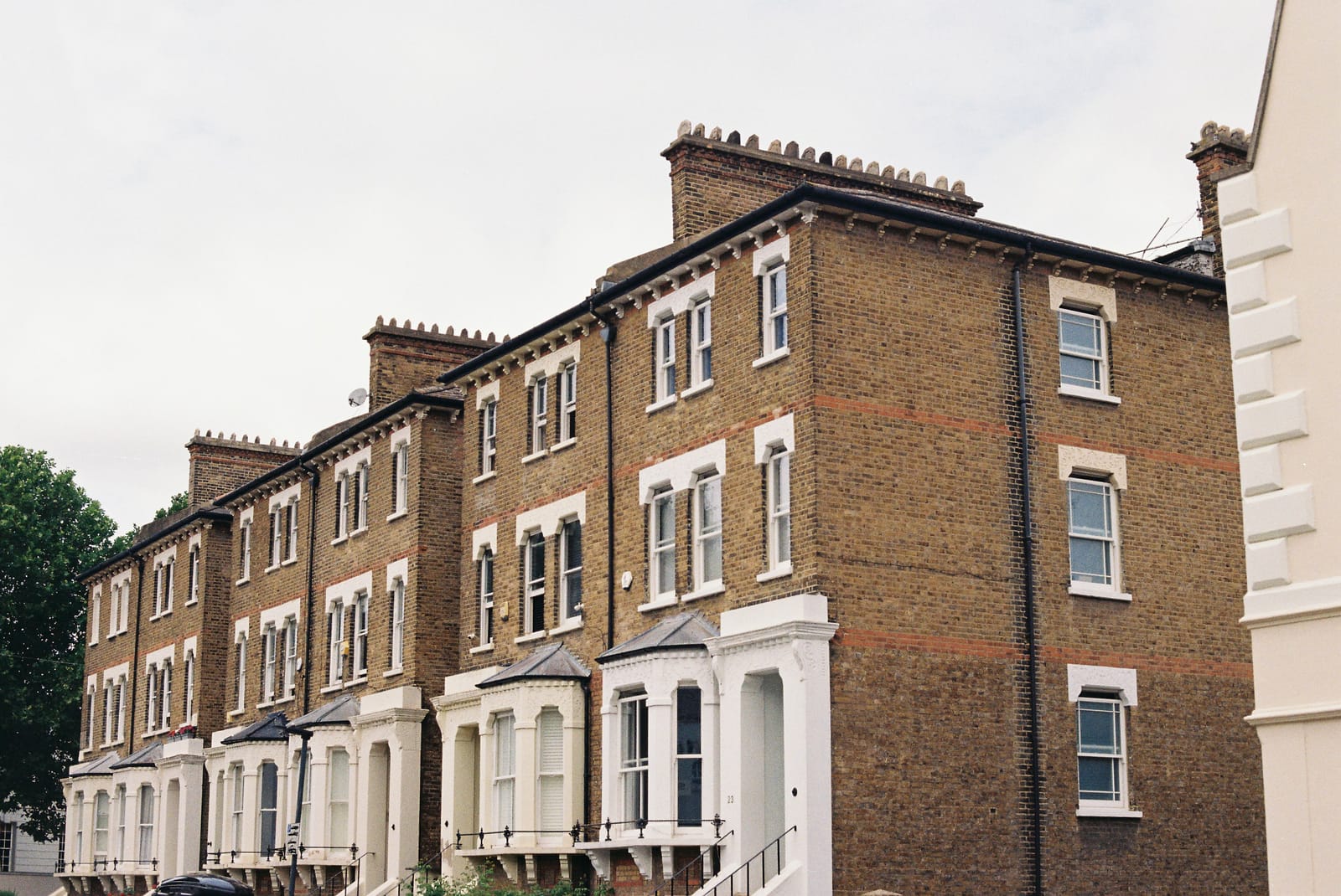 Three-storey yellow stock brick Victorian villas with white stucco ground-floor bays, sash windows and tall chimneys