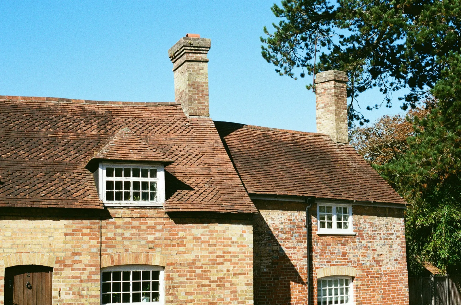 Brick cottage with a small pitched dormer in a clay-tiled roof, the kind of older roof where bats can roost
