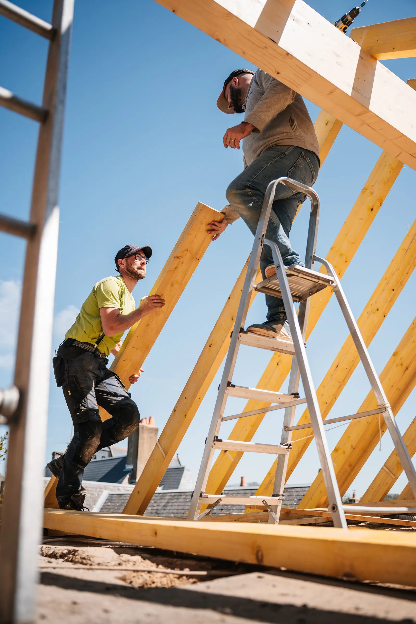Carpenters fixing new timber roof rafters from a ladder