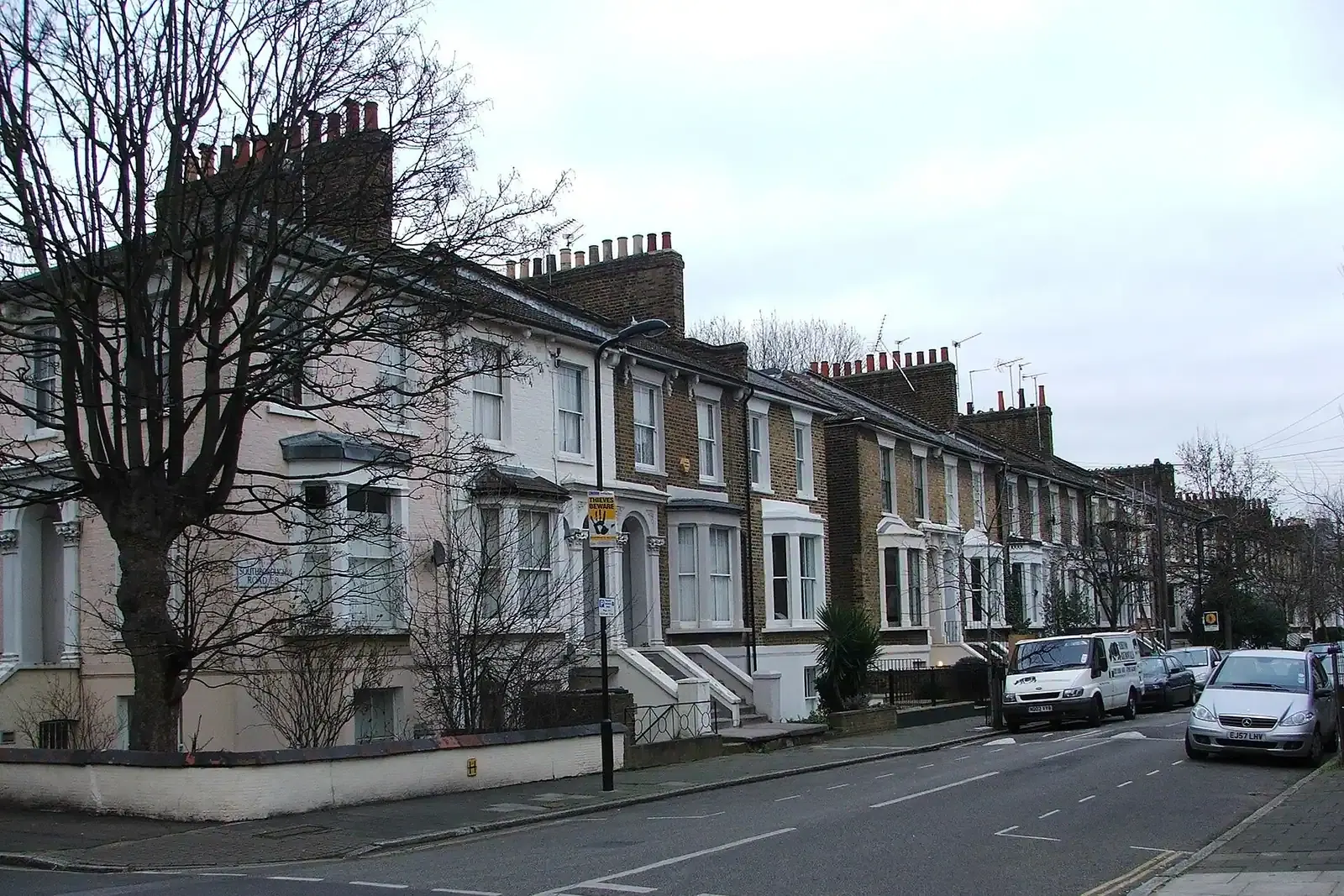 Victorian terrace on Southborough Road in Hackney with white window surrounds and tall chimney stacks, bare street trees and a white van