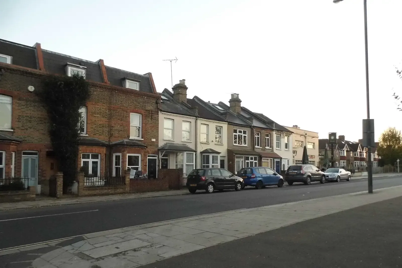 Row of brick terraced houses on Staines Road in Twickenham, some with roof windows, parked cars at the kerb