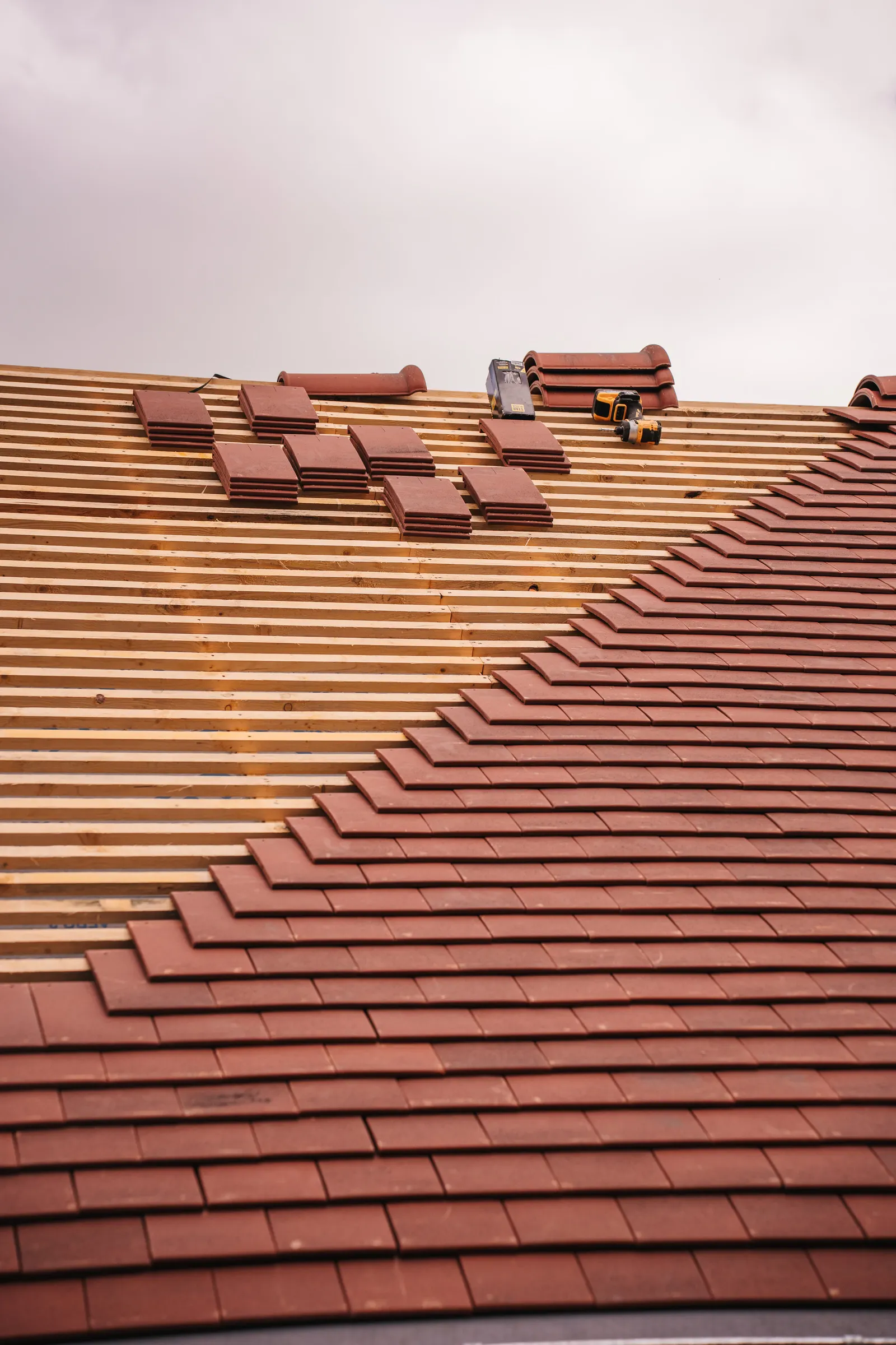 Clay roof tiles being laid onto new timber battens, the kind of material a planning condition asks you to agree before work starts