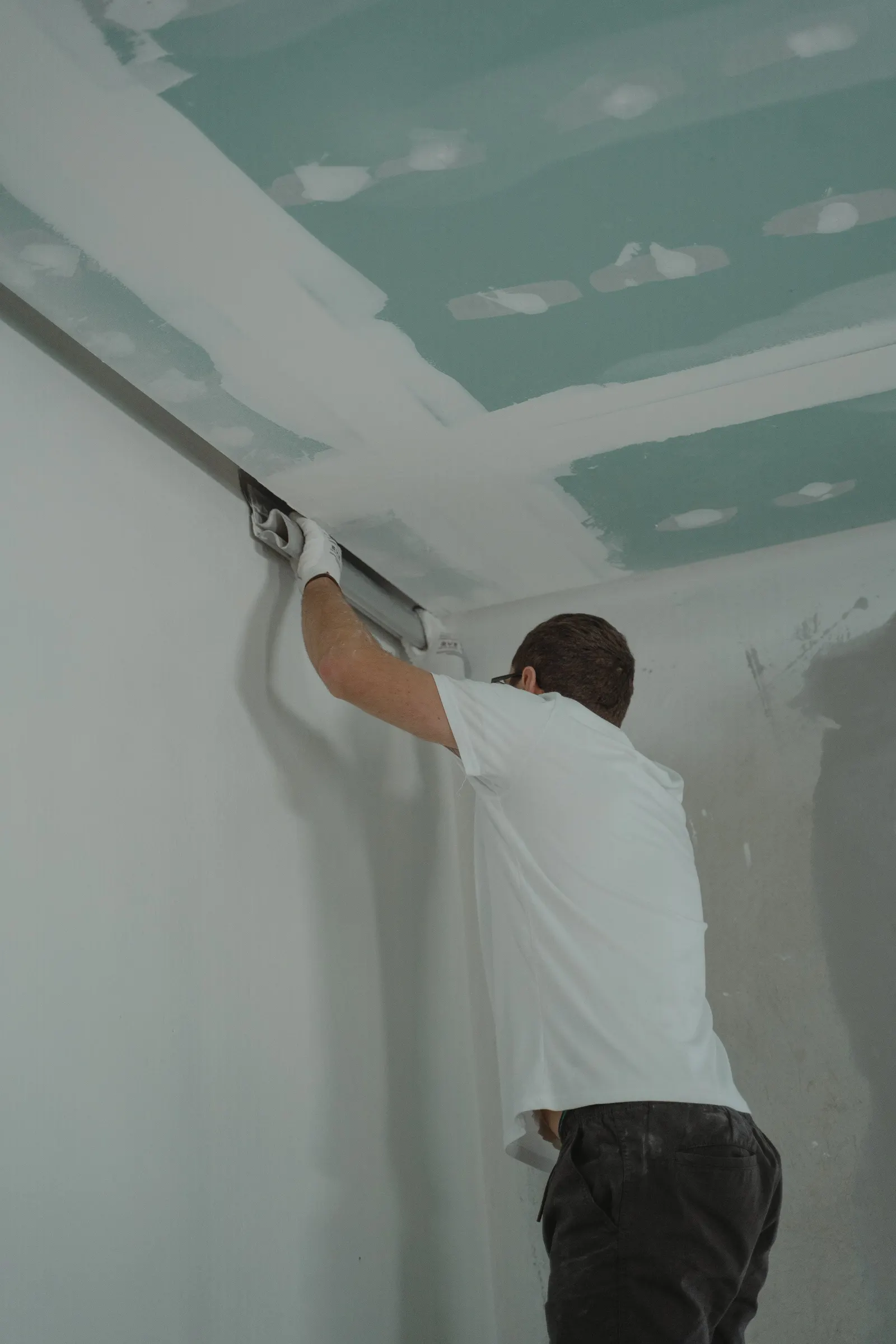 Plasterer finishing the join between a plasterboard ceiling and a wall, a finish that can hide the structure behind it