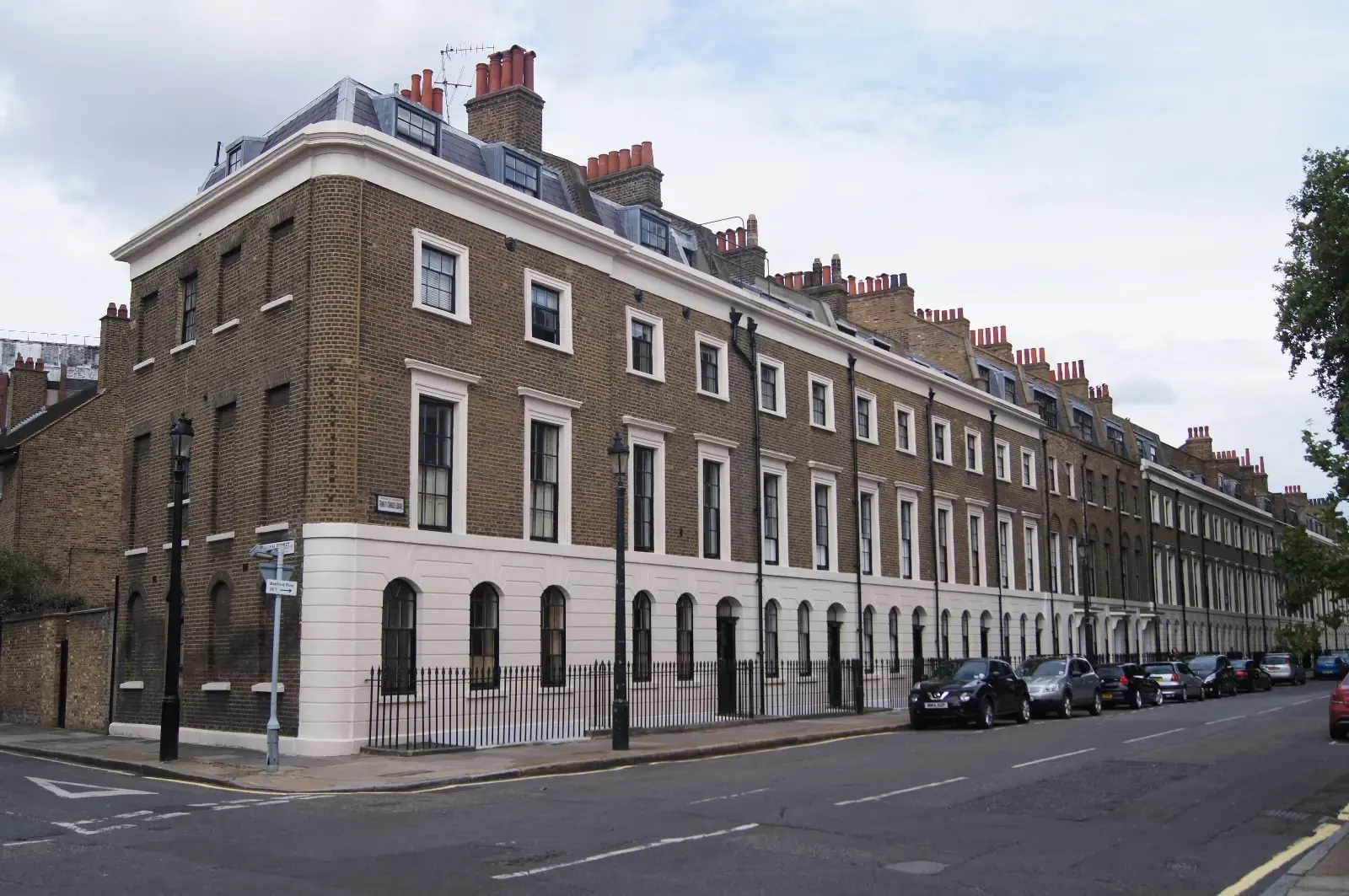 Long terrace of Georgian town houses with white stucco ground floor and brown brick above, on Trinity Street in Southwark
