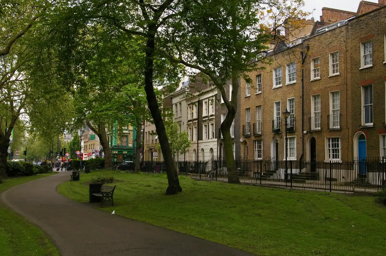 Georgian terrace of brown brick houses facing a leafy green on Paradise Row in Bethnal Green, a path curving through the park