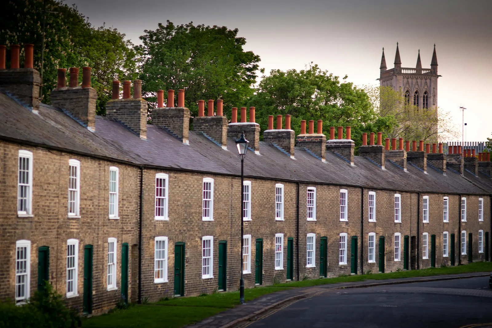 Long terrace of brick cottages leading to a church tower