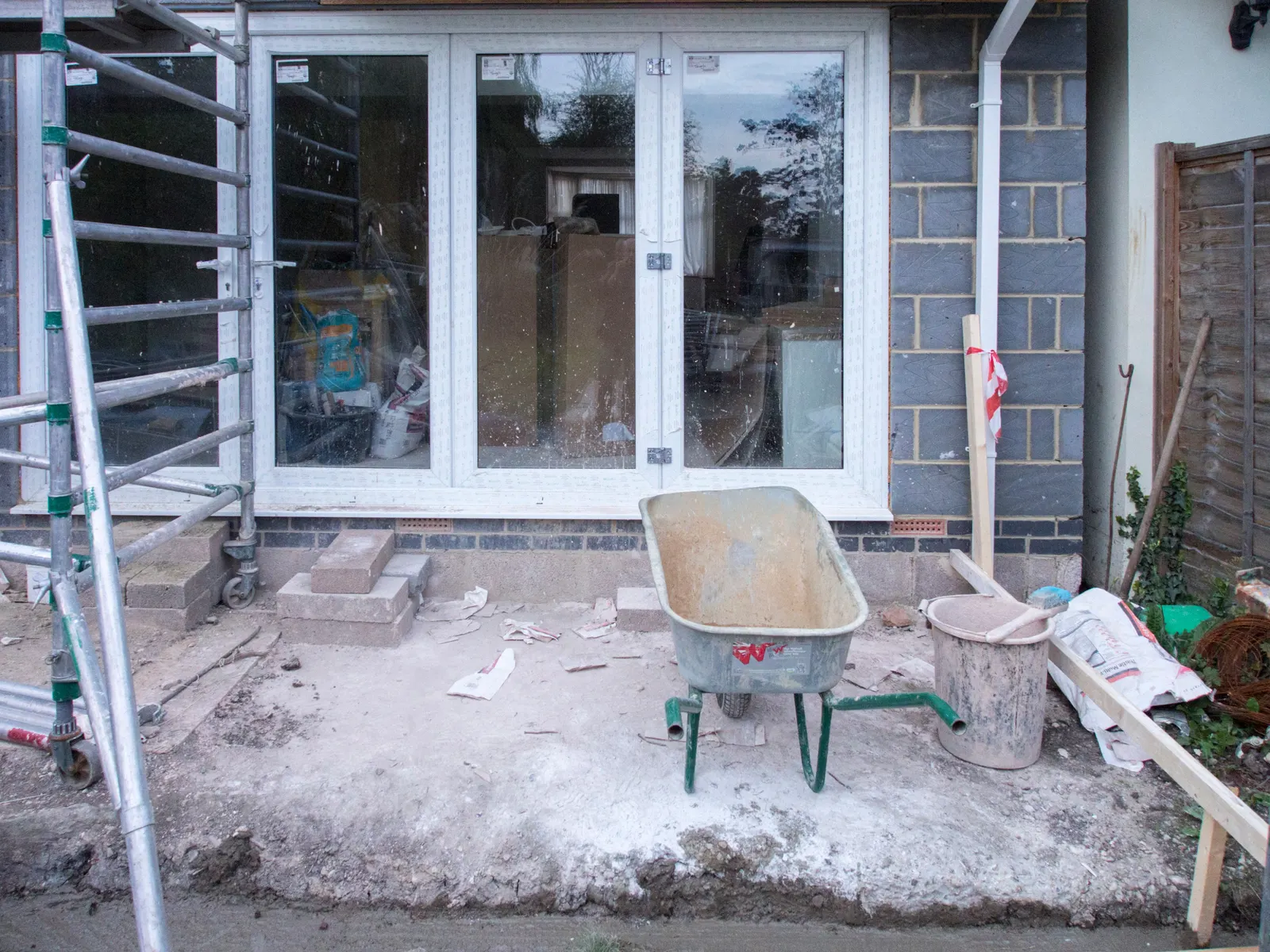 Rear wall of a house extension with new patio doors, blockwork up to the roof line and a scaffold tower still standing beside it